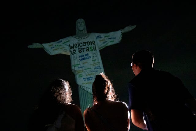 Fans look up at the Christ the Redeemer statue that is illuminated with a welcome message to American singer Taylor Swift, in Rio de Janeiro, Brazil