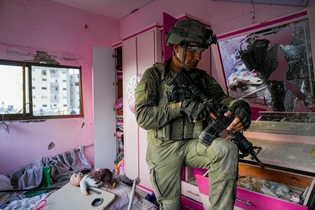 An Israeli soldier stands in an apartment during a ground operation in the Gaza Strip