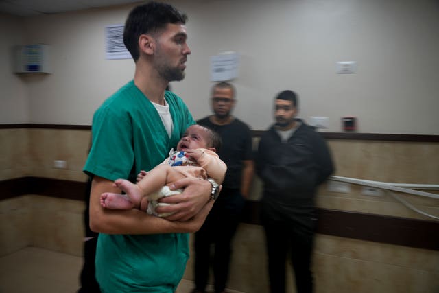 A Palestinian baby wounded in the Israeli bombardment of the Gaza Strip is brought to a hospital in Deir al-Balah