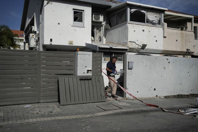 People inspect the damaged house in Ashkelon, Israel, after it was hit by a rocket fired from the Gaza Strip