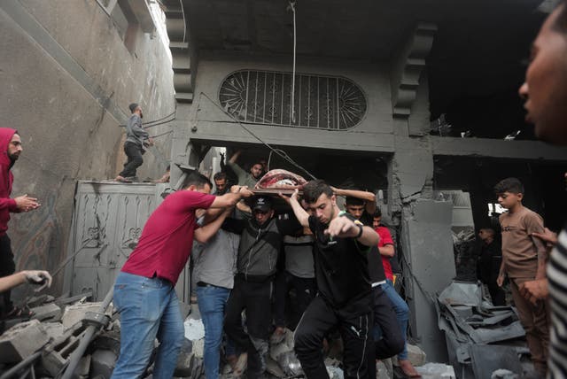 Palestinians evacuate an injured woman found under the rubble of a destroyed house following an Israeli airstrike in Khan Younis refugee camp, southern Gaza Strip, on Saturday