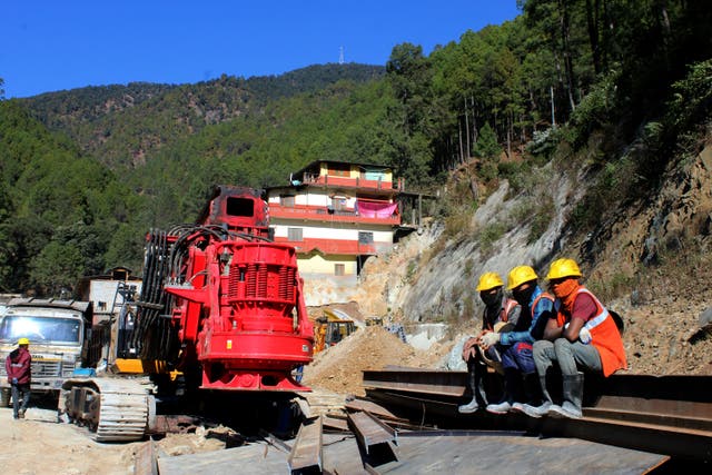 Rescuers rest at the site of a collapse tunnel in India