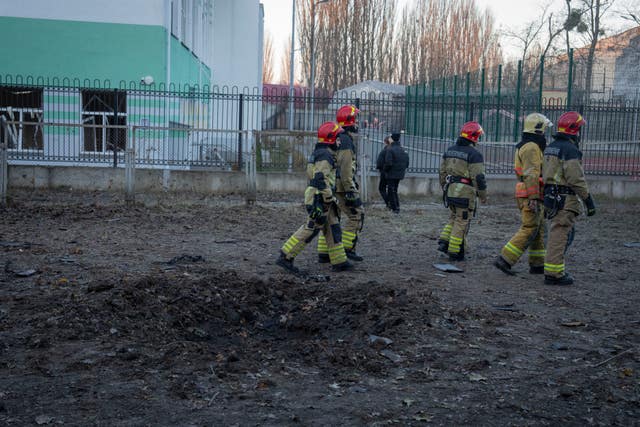 Firefighters pass a crater left by drone fragments following a Russian attack on Kyiv