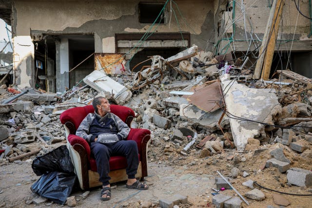 A Palestinian man sits in an armchair outside a destroyed building in Gaza City on Wednesday 