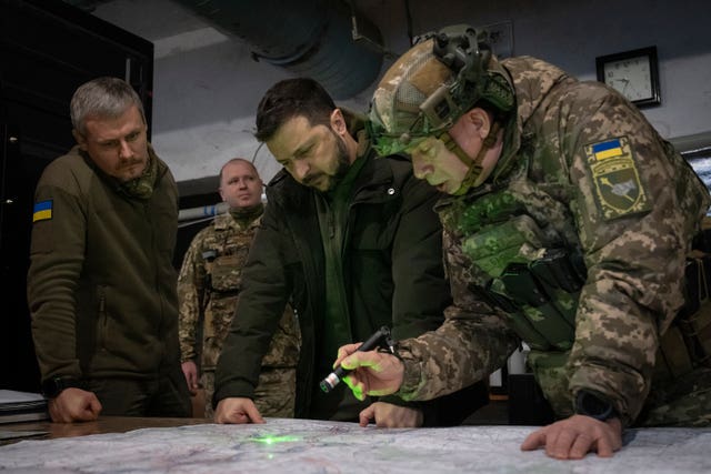 Ukrainian President Volodymyr Zelensky, middle, looks at a map during a visit to the frontline city of Kupiansk, Kharkiv region, Ukraine, on November 30