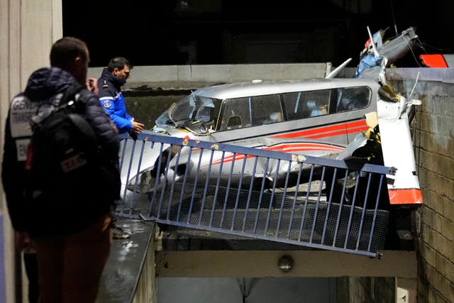 Police officers stand by a small plane that made an emergency landing in a residence in Villejuif, outside Paris