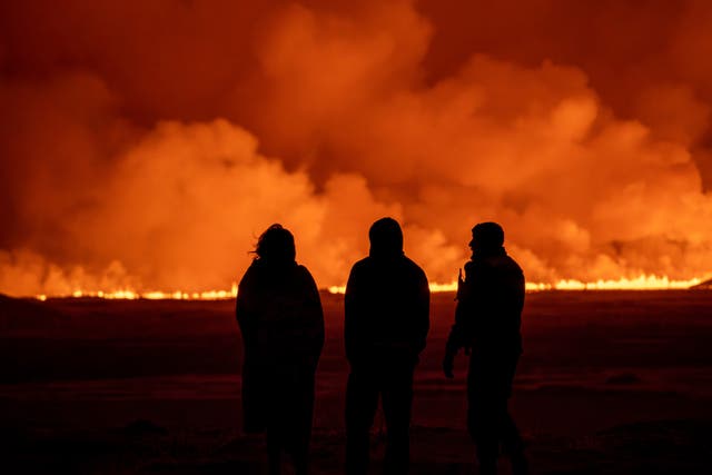 People watch as the night sky is illuminated by the erupting volcano