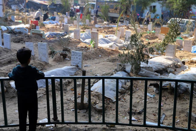 A Palestinian child looks at the graves of people killed in the Israeli bombardment of the Gaza Strip and buried inside the Shifa Hospital grounds