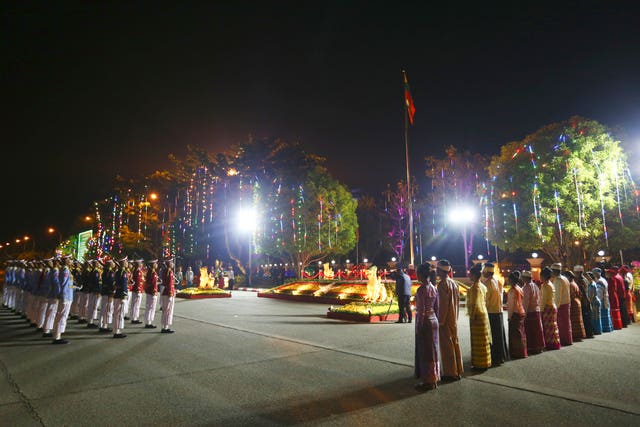 Members of an honour guard and representatives of national ethnic races salute their national flag 