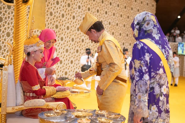 Brunei’s Sultan Hassanal Bolkiah, centre right, pouring scented oil on the hands of Brunei’s Prince Abdul Mateen’s bride Yang Mulia Anisha Rosnah, left, during the royal powdering ceremony at Istana Nurul Iman, ahead of his wedding to Anisha Rosnah, in Bandar Seri Begawan, Brunei 