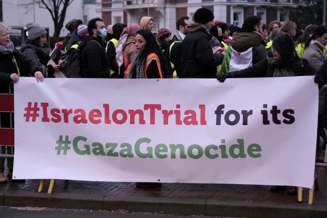 People stand by a banner outside the International Court of Justice