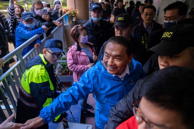 Kuomintang candidate Hou Yu-ih (centre) greets supporters as he leaves a polling station