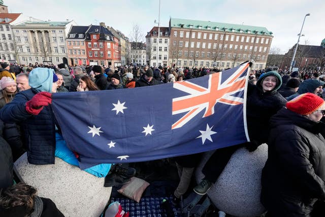 People with an Australia flag wait at Christiansborg castle in Copenhagen, Denmark, Sunday, Jan. 14, 2024. Denmark’s Crown Prince Frederik takes over the crown on Sunday from his mother, Queen Margrethe II, who is breaking with centuries of Danish royal tradition and retiring after a 52-year reign