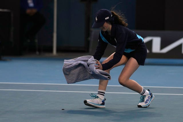 A ball girl tries to catch a bug