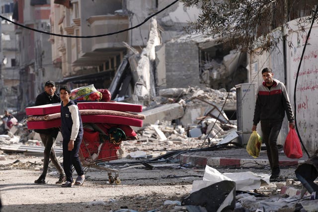Palestinians walk through destruction in the Nusseirat refugee camp in the Gaza Strip on Tuesday