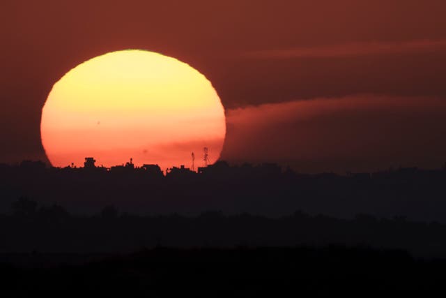 The sun sets behind buildings in the Gaza Strip on Tuesday