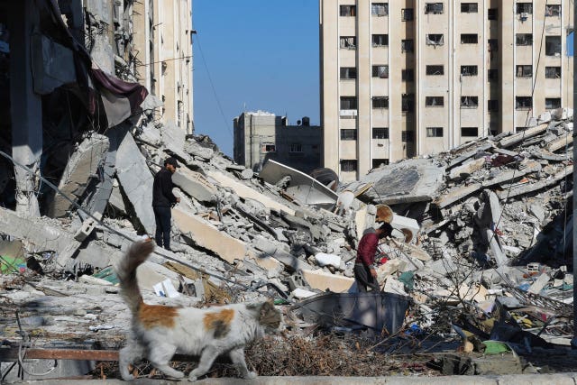 Palestinians walk through destruction from the Israeli bombardment in the Nusseirat refugee camp in the Gaza Strip on Friday