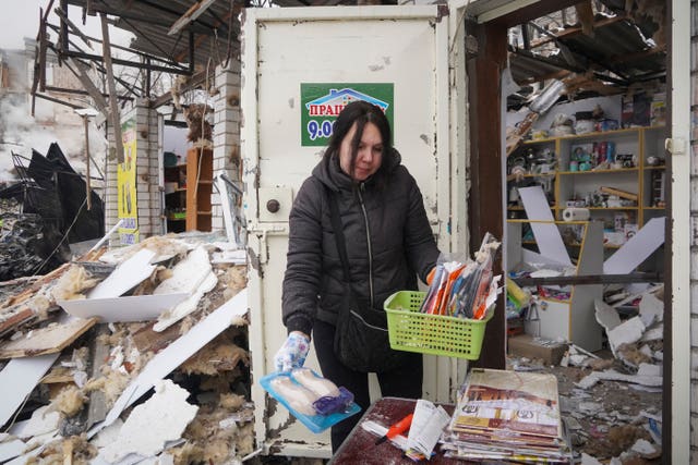 A vendor collects goods from her shop damaged by a Russian rocket attack in Kharkiv 