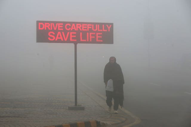 A man walks past a sign that reads “Drive carefully save life” in Peshawar, Pakistan