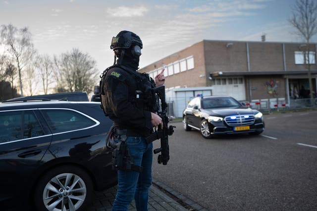 Masked and armed Dutch police guard a transport of some of the suspects who arrived at the high security court building where the trial opened in Amsterdam 