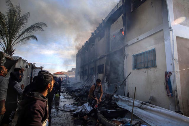 Palestinians try to extinguish a fire at a UNRWA vocational training centre which displaced people use as a shelter in Khan Younis