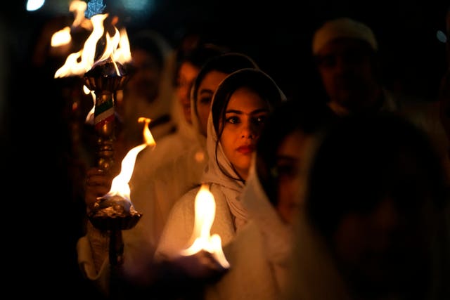 A Zoroastrian youth carries a torch to set fire to a prepared pile of wood