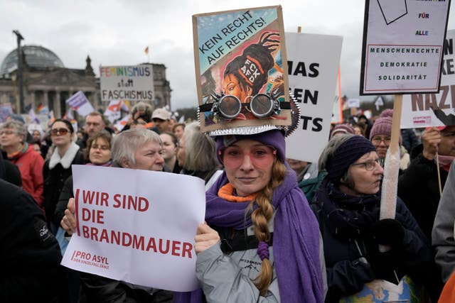 A woman holds a sign reading ‘We are the firewall’ in front of Germany’s parliament Reichstag at a demonstration against the AfD party and right-wing extremism in Berlin, Germany