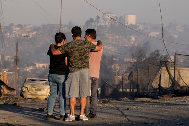 Locals look at burnt-out houses and other debris after a forest fire reached their neighbourhood in Vina del Mar, Chile