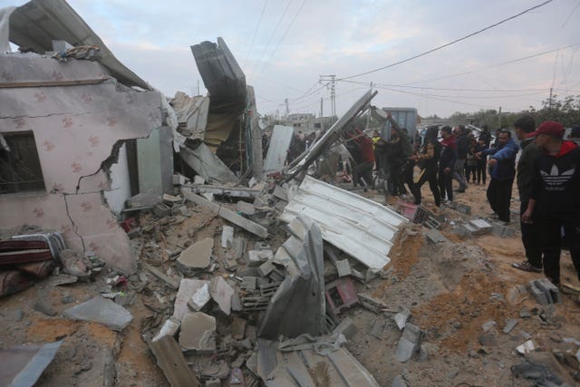Palestinians look at a house destroyed in an Israeli strike in Rafah 