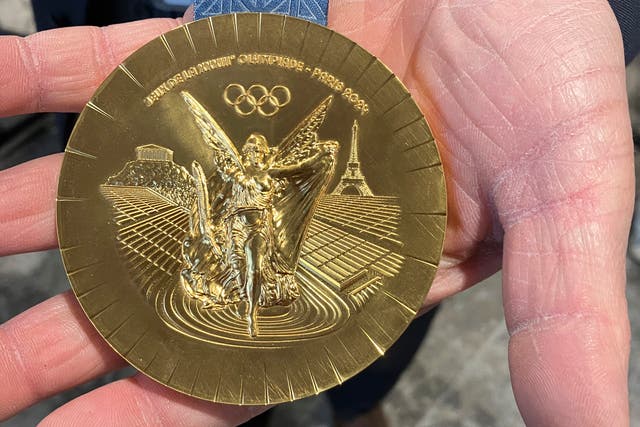 A side of the Paris 2024 Olympic gold medal, featuring an Eiffel Tower on the right, is presented in Paris