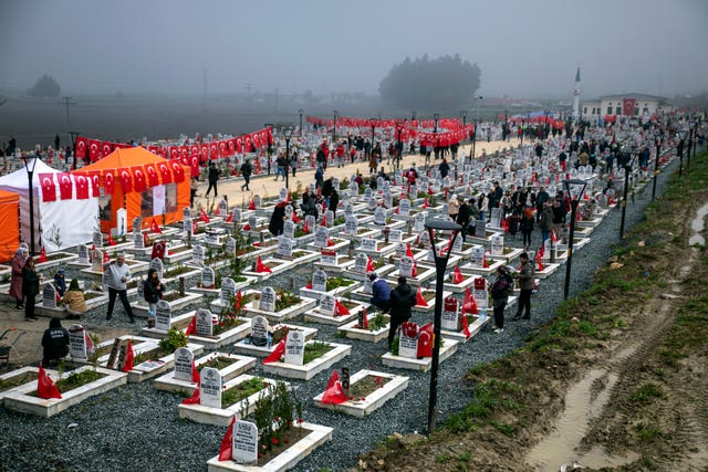 People visit graves in a cemetery where some of the victims of the earthquake are buried 