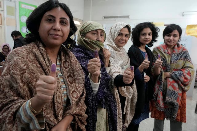 Women show their marked thumbs after casting their vote at a polling station during the country’s parliamentary elections in Karachi, Pakistan