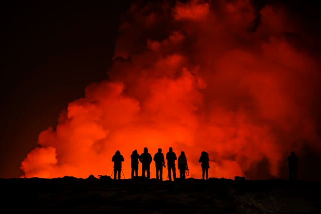 People look at the volcano erupting north of Grindavik, Iceland
