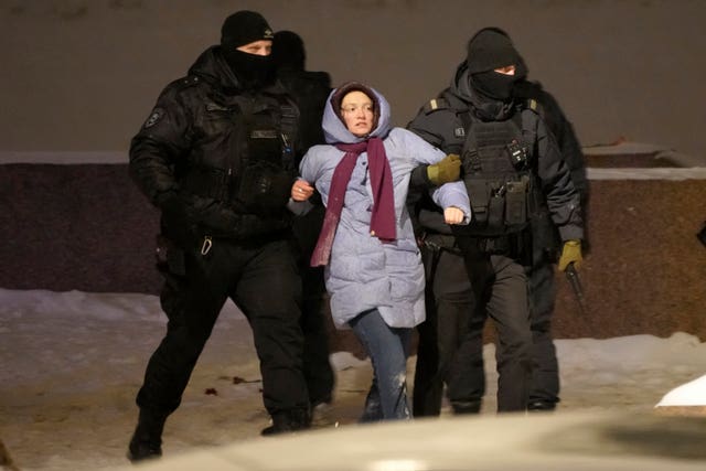 Police officers detain a woman who laid flowers for Alexei Navalny at the Memorial to Victims of Political Repression in St Petersburg, Russia