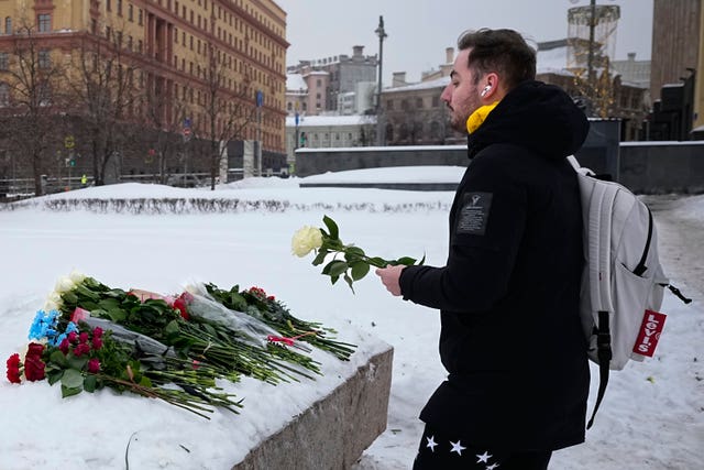 A man lays flowers paying last respects to Alexei Navalny at the monument, a large boulder from the Solovetsky islands, where the first camp of the Gulag political prison system was established, with the historical the Federal Security Service (FSB, Soviet KGB successor) building in the background, in Moscow, Russia