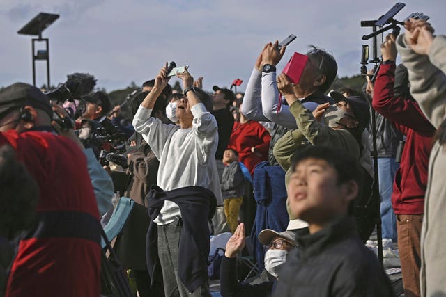 People in Minamitane town, Kagoshima, southern Japan, watch as an H3 rocket lifts off from Tanegashima Space Centre