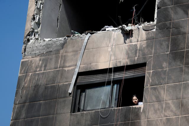 A girl looks out from a window of a residential building after a reported Israeli attack on Syria (Omar Sanadiki/AP)