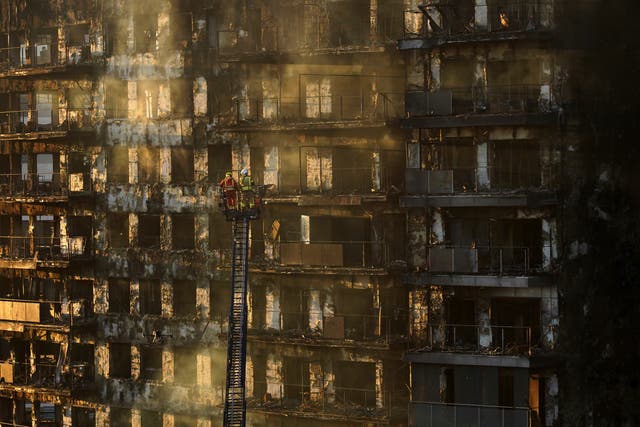 Firefighters work at a burned block building in Valencia, Spain 