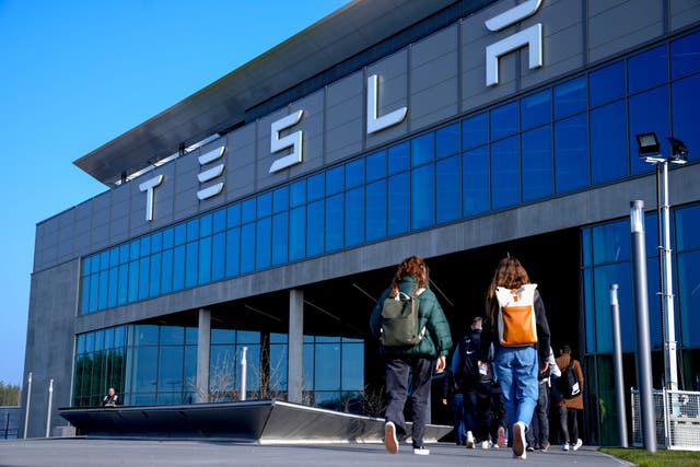 People walk to the Tesla Gigafactory for electric cars in Gruenheide near Berlin, Germany (Ebrahim Noroozi/AP)