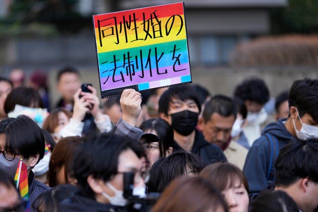 A supporter for the LGBT+ community holds a poster 
