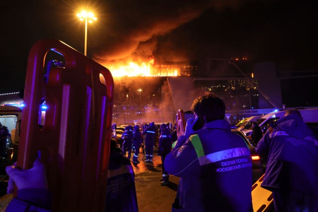 A medic stands near ambulances parked outside the burning building of Crocus City Hall on the western edge of Moscow, Russia 