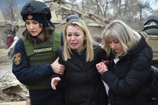 An emergency service psychologist, left, comforts a woman at the site of Russia’s air attack, in Zaporizhzhia, Ukraine 