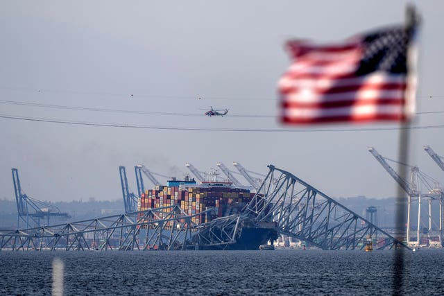 A US flag flies before the wreckage