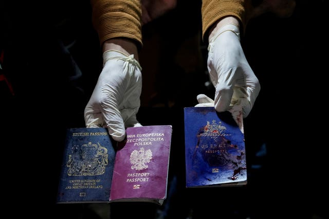 A man displays blood-stained British, Polish, and Australian passports after the air strike 