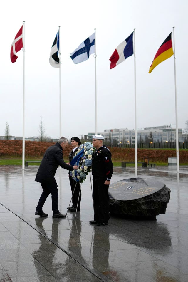 Nato secretary general Jens Stoltenberg, left, adjusts a ribbon during a wreath-laying ceremony at Nato headquarters in Brussels