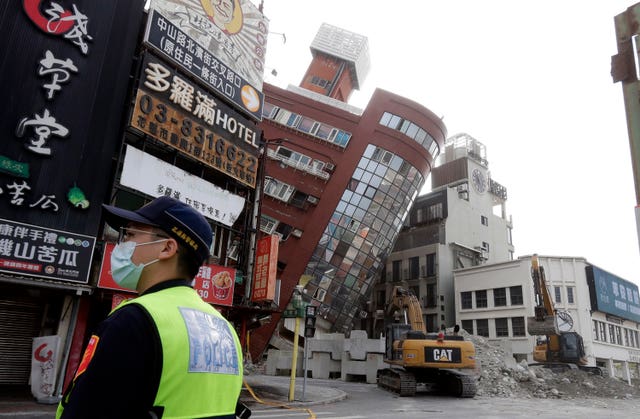 A police officer stands guard near a partially collapsed building a day after a powerful earthquake struck in Hualien City, eastern Taiwan