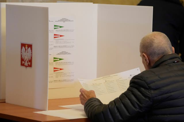 A man examines his ballot during local elections in Warsaw, Poland