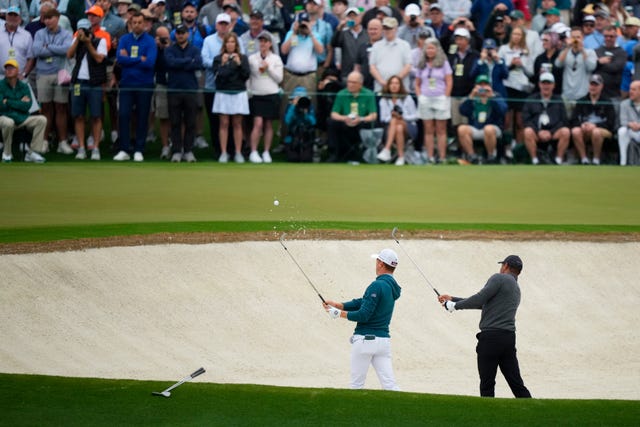 Justin Thomas, left, and Tiger Woods hit out of a bunker on the second hole in practice at the Masters