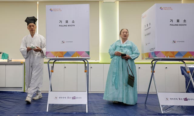 People wearing traditional attire cast their votes at a polling station in Nonsan, South Korea
