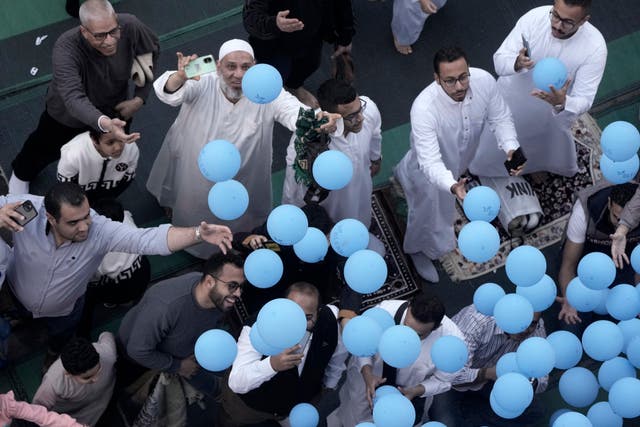 People try to catch free balloons distributed during Eid al-Fitr in Cairo
